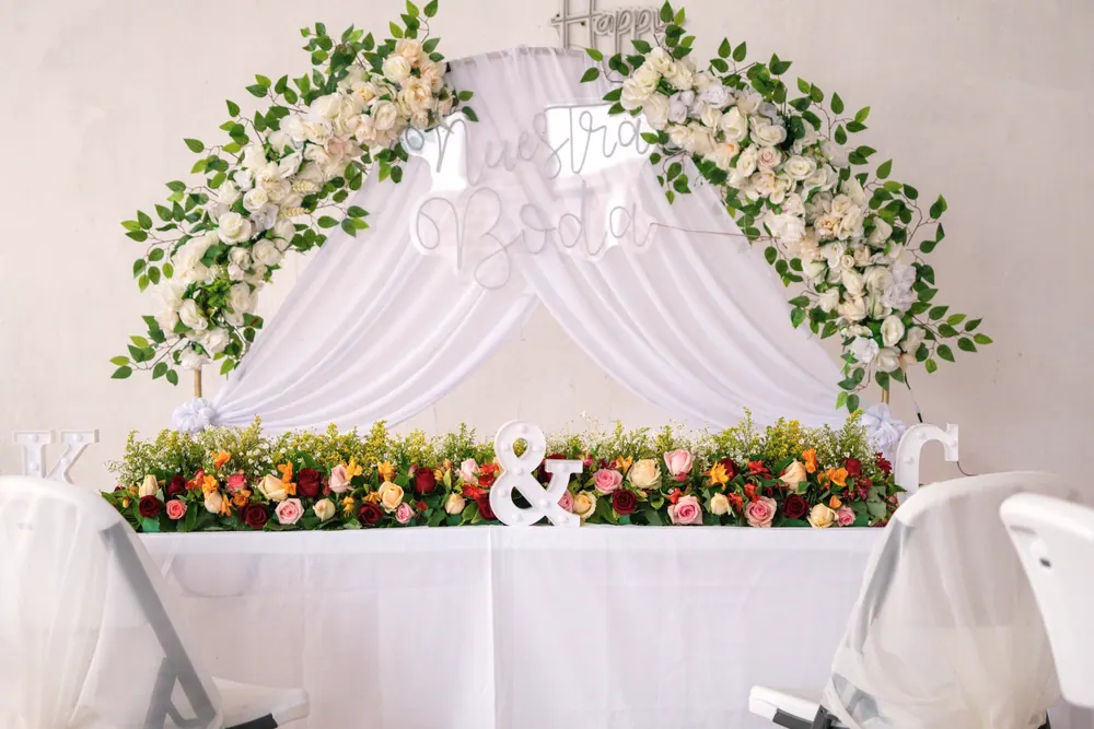 Mesa de novios con arco floral blanco